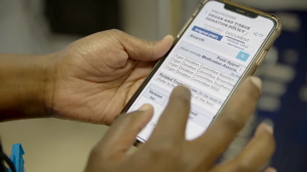 A member of staff scrolling the Organ and Tissue Donation Policy in MyStaff on their phone